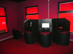 Trzy komputery do gier hazardowych stoją w pomieszczeniu pomalowanym na czerwony kolor. 