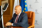 Minister Tadeusz Kościński przed ekranem komputera podczas spotkania prasowego online