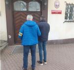 Funkcjonariusz KAS z zatrzymanym mężczyzną wchodzą do budynku Prokuratury Rejonowej w Gdyni.