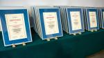 Wiele certyfikatów dla nagrodzonych urzędów skarbowych ułożonych na stole