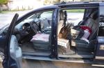 Samochód osobowy z otwartymi drzwiami, na fotelach kartony i butle plastikowe.