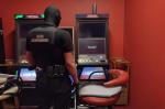 Funkcjonariusz Służby Celno-Skarbowej stoi przed automatami do gier hazardowych w pomieszczeniu.  