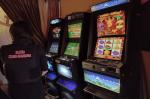Funkcjonariuszka stoi przed trzema automatami do gier hazardowych.