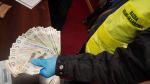 Funkcjonariusz trzyma w ręku znalezione banknoty.