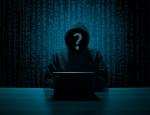 Haker, zacieniony mężczyzna w kapturze siedzi przed komputerem